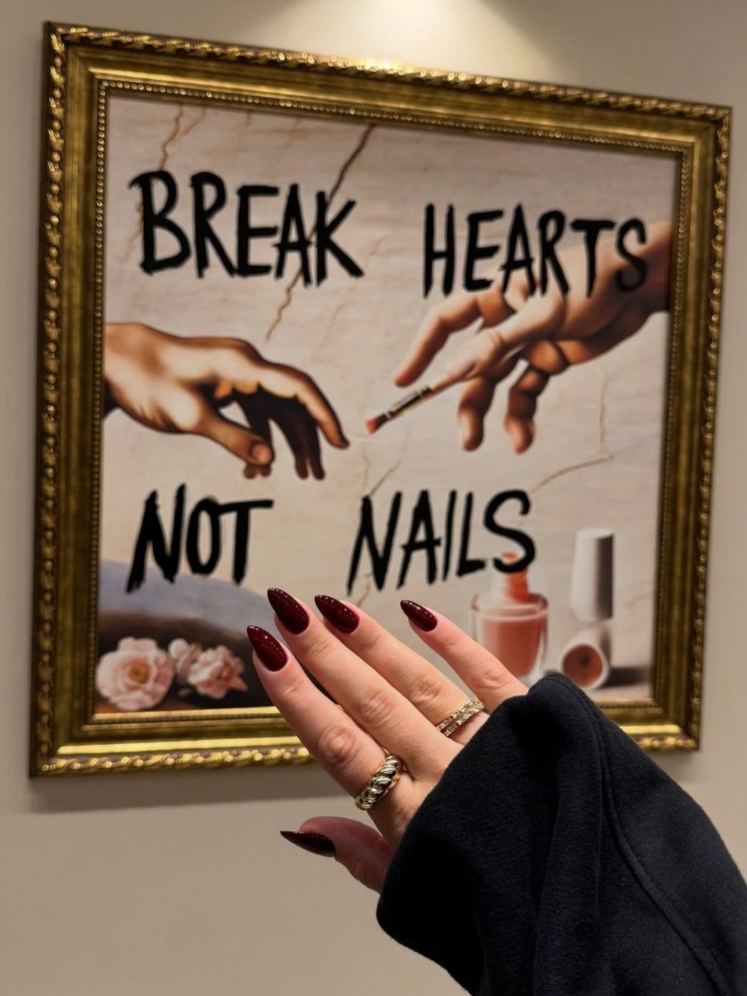 Burgundy almond nails in front of framed art inside Glamour Nail